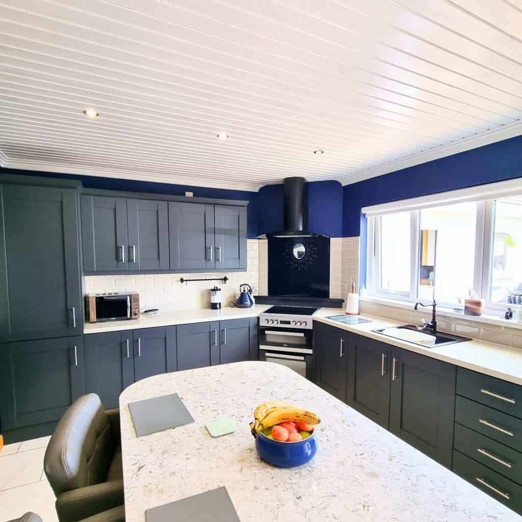 Vibrant navy blue kitchen cabinets with white subway tile backsplash and modern appliances, showcasing professional interior painting services in Portstewart for stylish home upgrades.