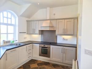 Bright white kitchen with modern cabinetry and stainless steel appliances, featuring fresh interior painting in Portstewart by G&E Interior Painting.