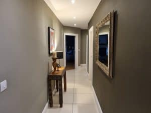 Modern hallway interior painted with stylish gray tones, featuring decorative wall art, a classic wooden console table, and an ornate framed mirror, showcasing professional interior painting by G&E Interior Painting in Portstewart.